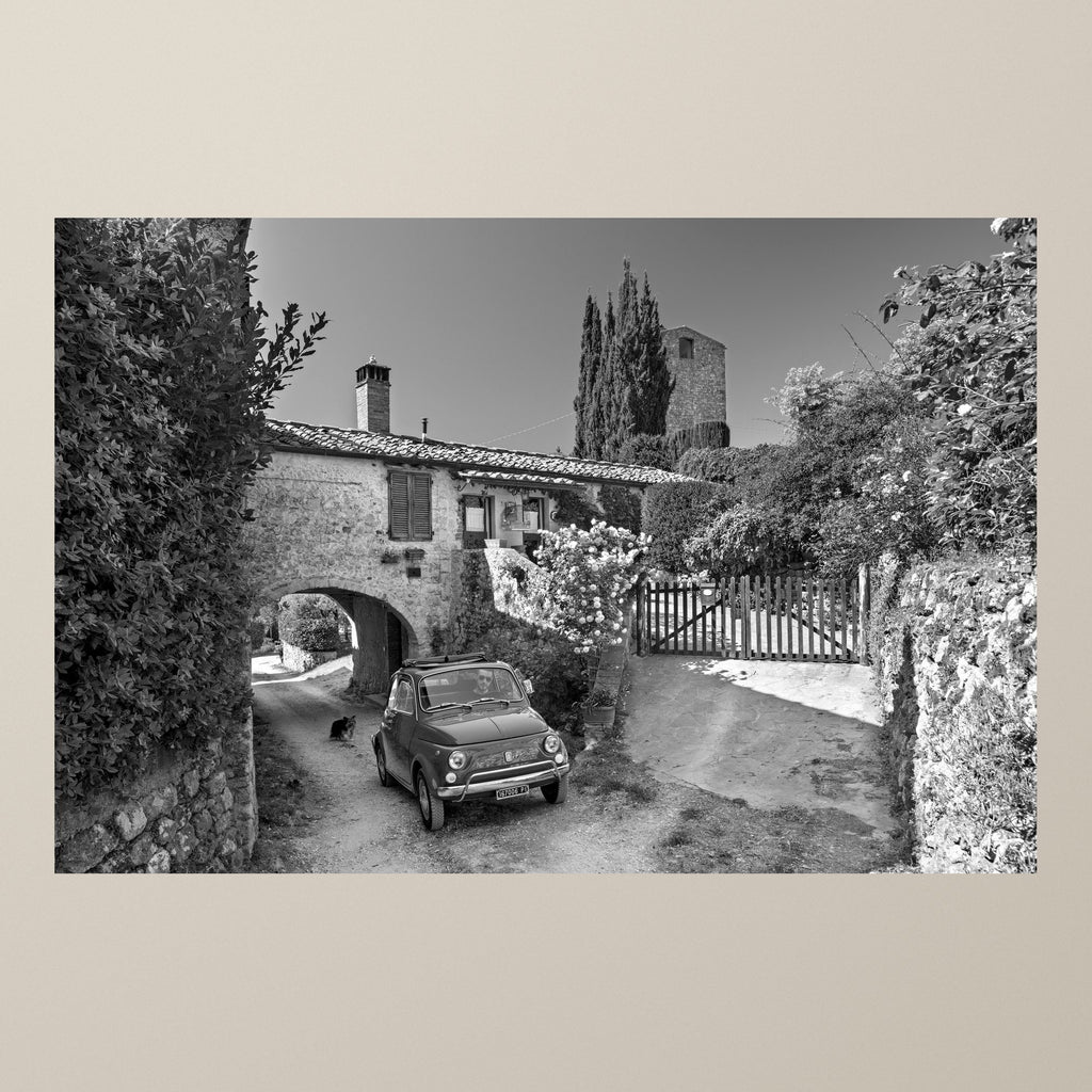 Beyond the Arch – A Fiat 500 beside an old stone archway, a medieval tower rising behind the trees – photograph by Duccio Nacci