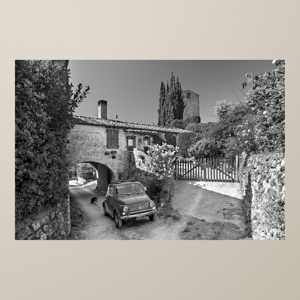 Beyond the Arch – A Fiat 500 beside an old stone archway, a medieval tower rising behind the trees – photograph by Duccio Nacci