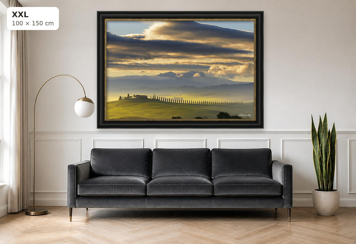 Dawn in Val d’Orcia – fine art print by Duccio Nacci, size XXL with black and gold frame shown above a sofa
