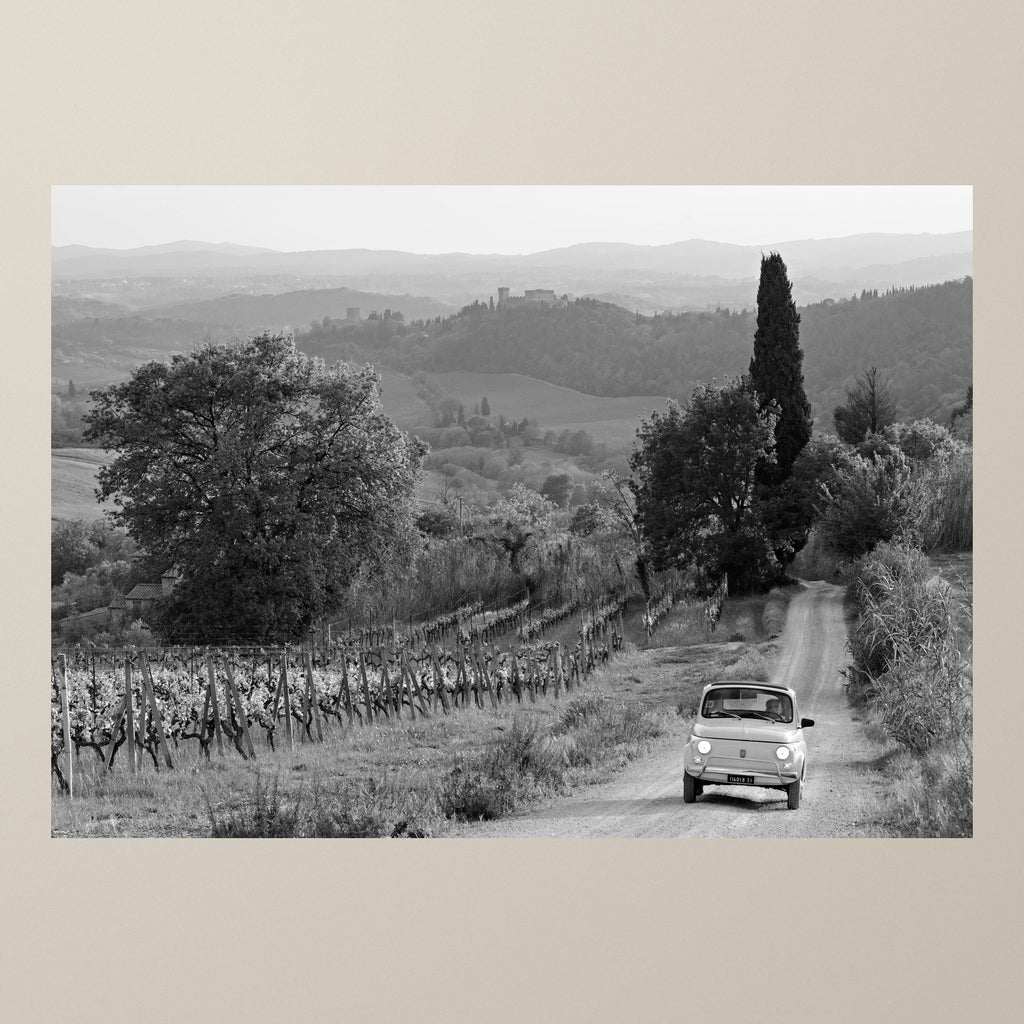Journey Through the Vineyards – A white Fiat 500 on a gravel lane between vineyards in the Chianti hills – photograph by Duccio Nacci