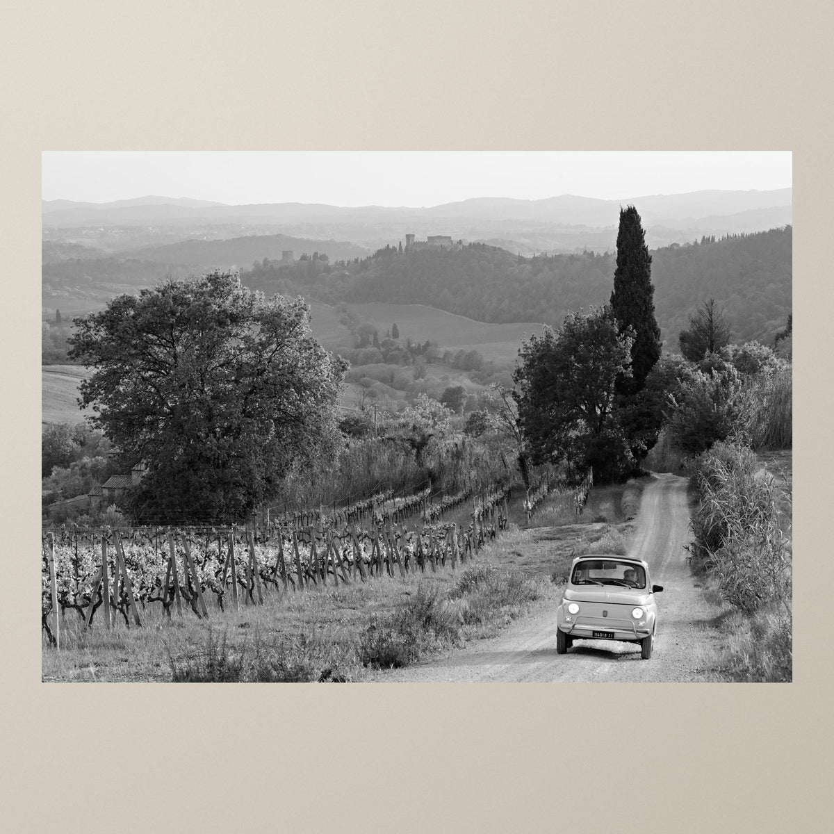 Journey Through the Vineyards – A white Fiat 500 on a gravel lane between vineyards in the Chianti hills – photograph by Duccio Nacci