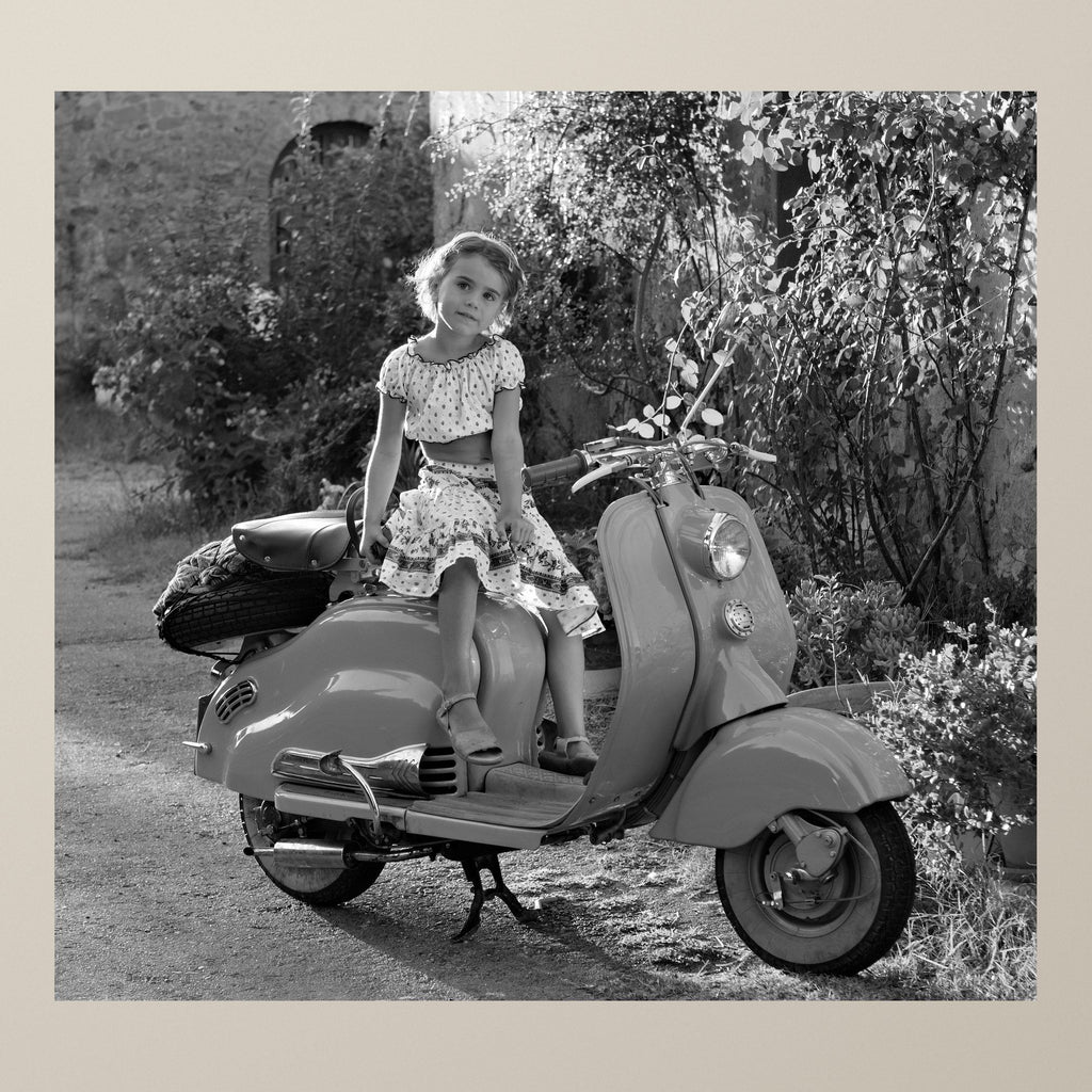 Lambretta Dreamscape – A little girl sitting on a gleaming scooter in a Chianti village, low sun behind – photograph by Duccio Nacci