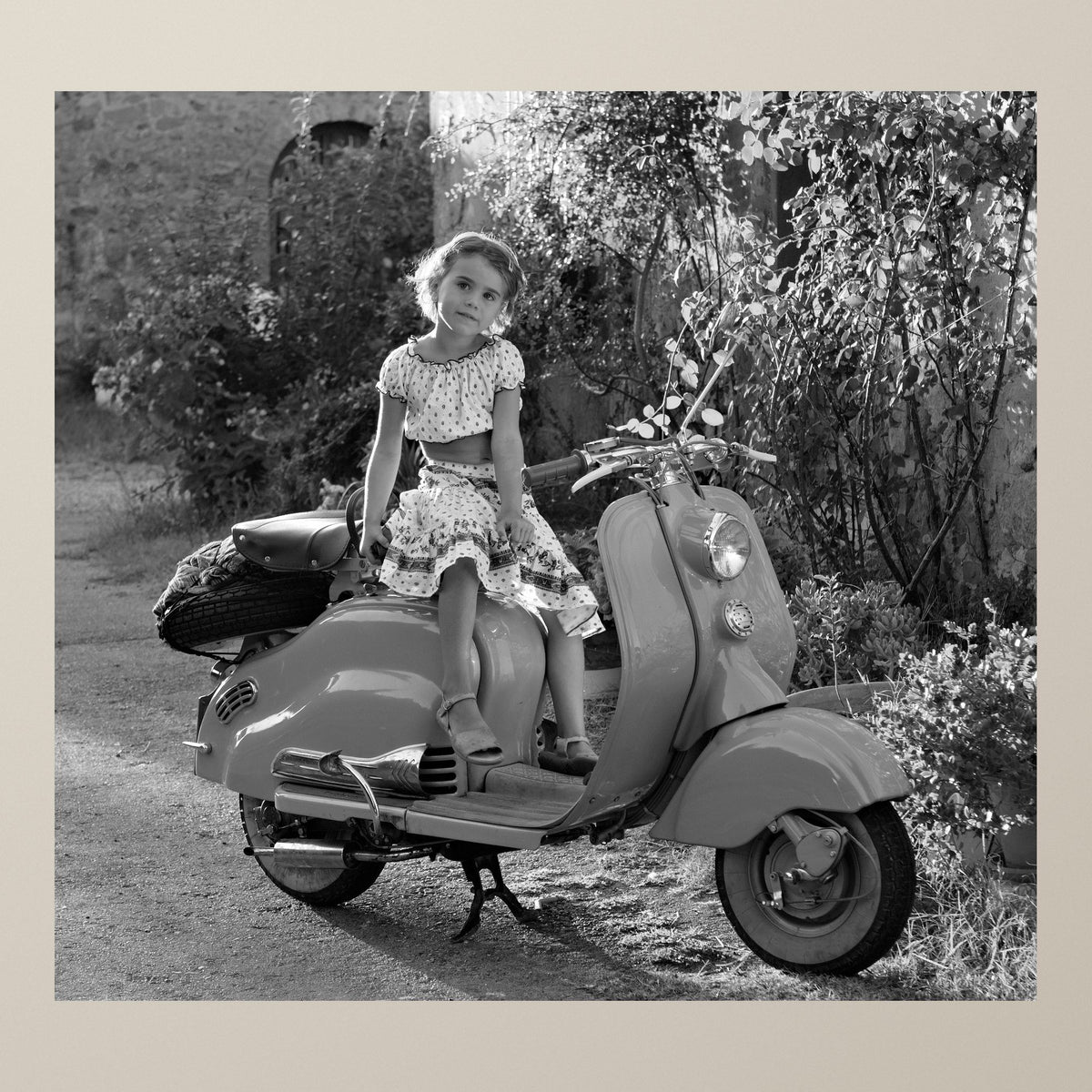 Lambretta Dreamscape – A little girl sitting on a gleaming scooter in a Chianti village, low sun behind – photograph by Duccio Nacci