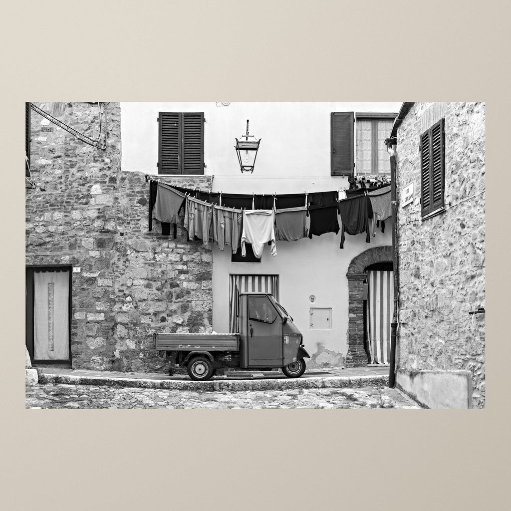 Stories on the Line – A Piaggio Ape parked beneath a line of laundry drying in the sun – photograph by Duccio Nacci
