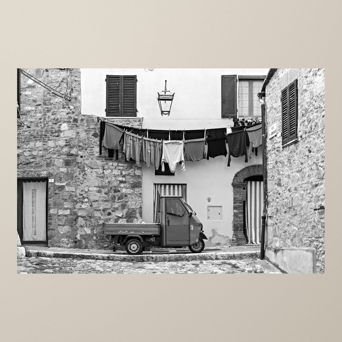 Stories on the Line – A Piaggio Ape parked beneath a line of laundry drying in the sun – photograph by Duccio Nacci