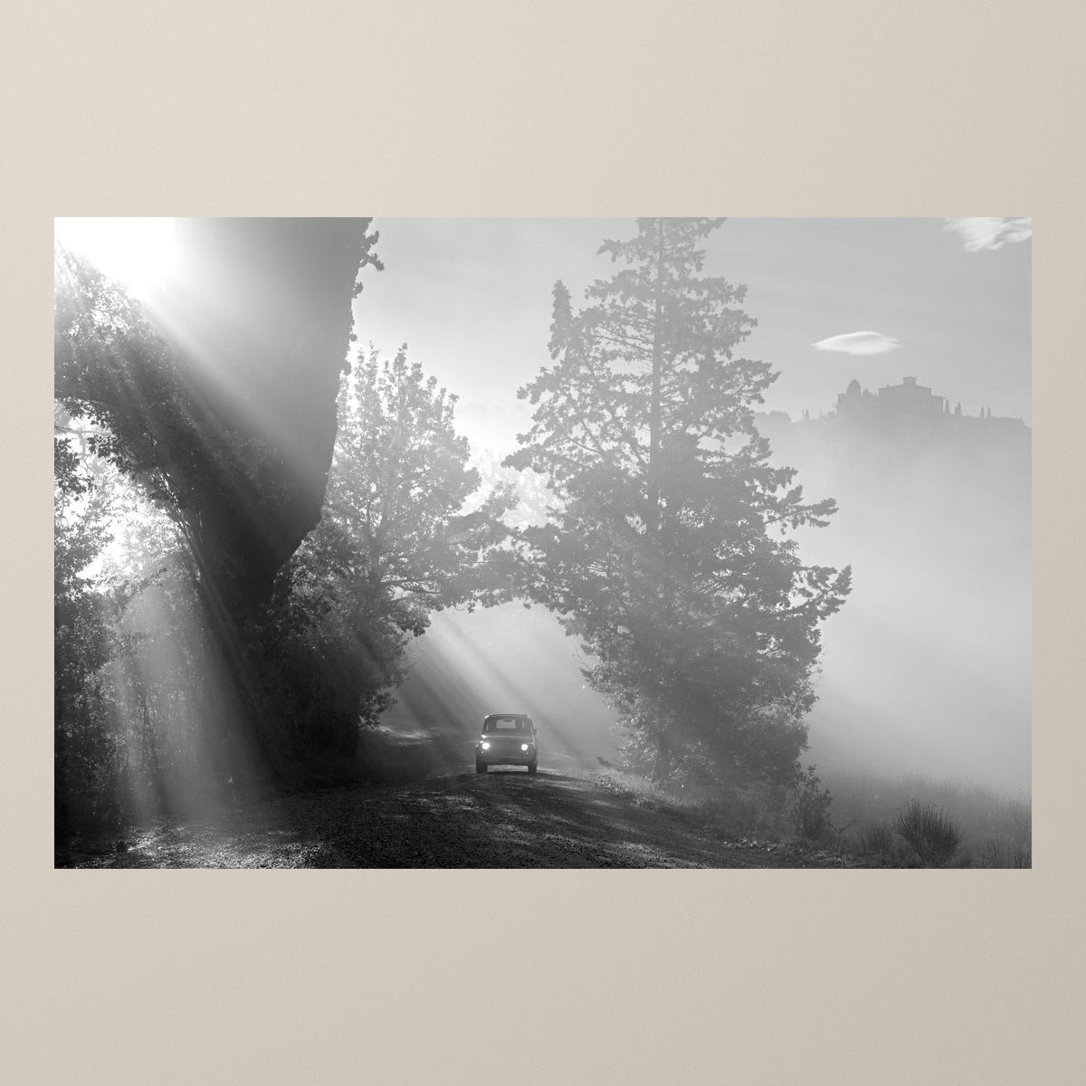 The Path of Light – Sunbeams break through trees and morning mist above a Fiat 500 on a Tuscan road – photograph by Duccio Nacci