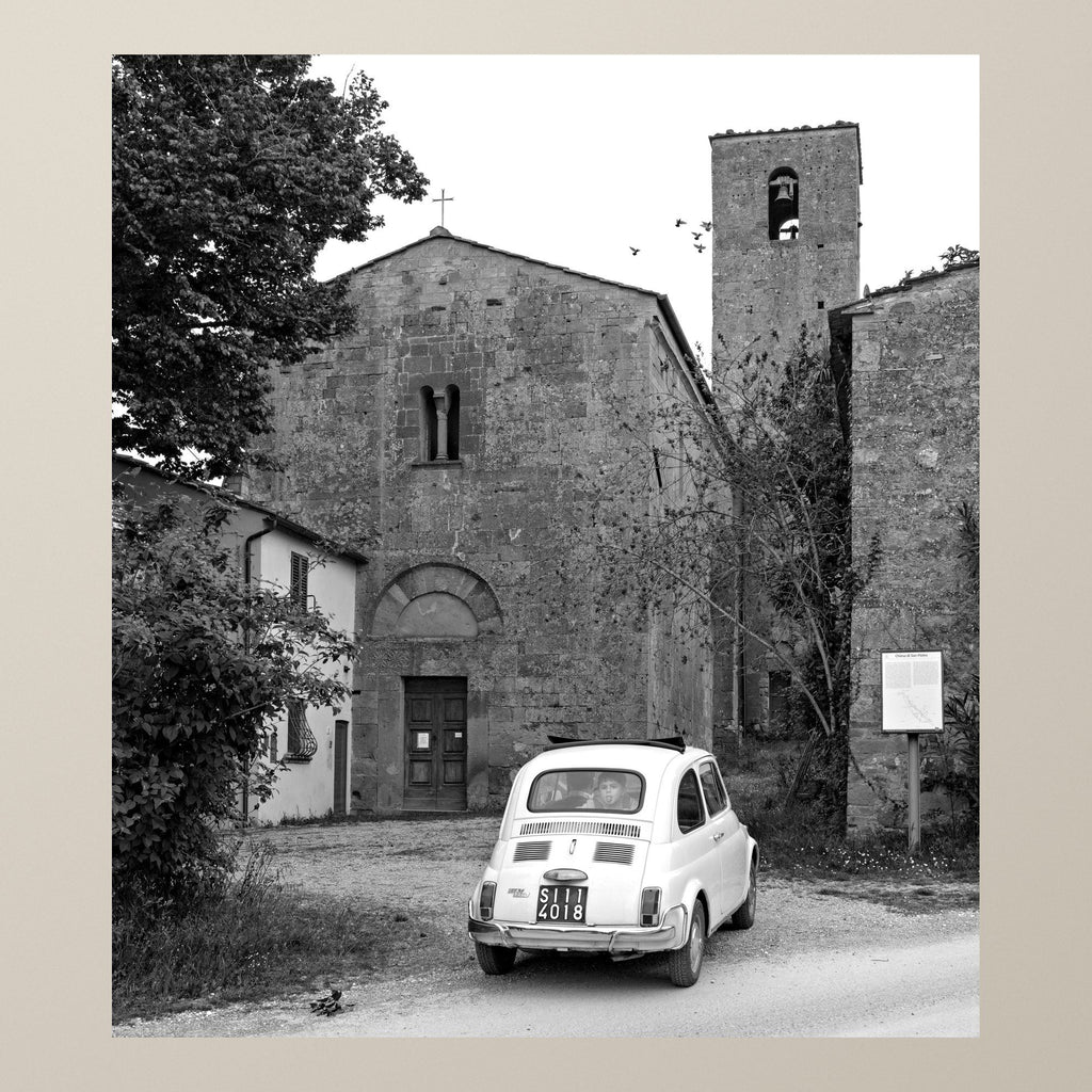 The White 500 – A white Fiat 500 parked before the stone façade of a Romanesque church – photograph by Duccio Nacci