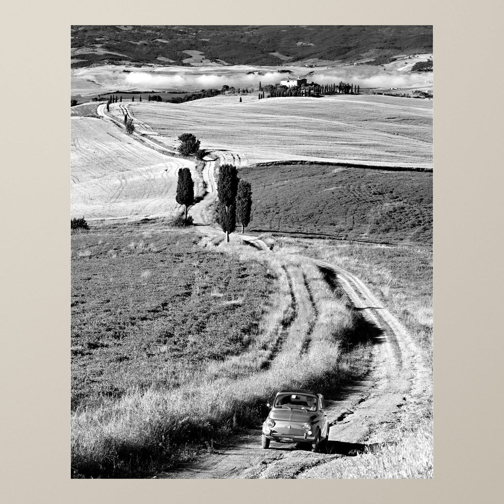 Tuscan Countryside – Cypresses frame a Fiat 500 on a dirt road winding through the Tuscan hills – photograph by Duccio Nacci